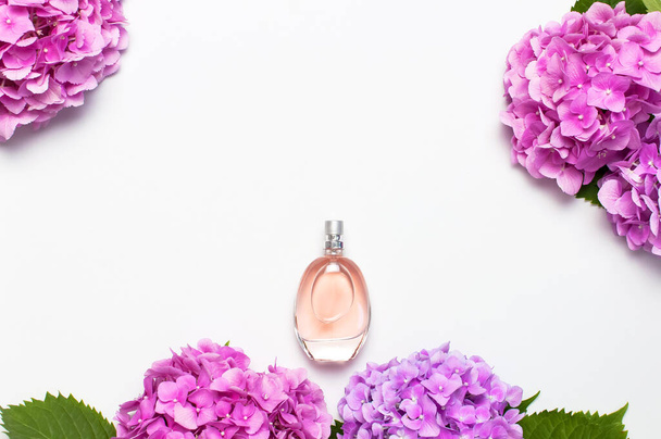 Frasco de perfume e flores de hortênsia rosa no fundo cinza claro vista superior Flat lay espaço de cópia. Perfumaria, cosméticos, acessórios femininos, coleção de fragrâncias. Frasco de perfume delicado
 - Foto, Imagem