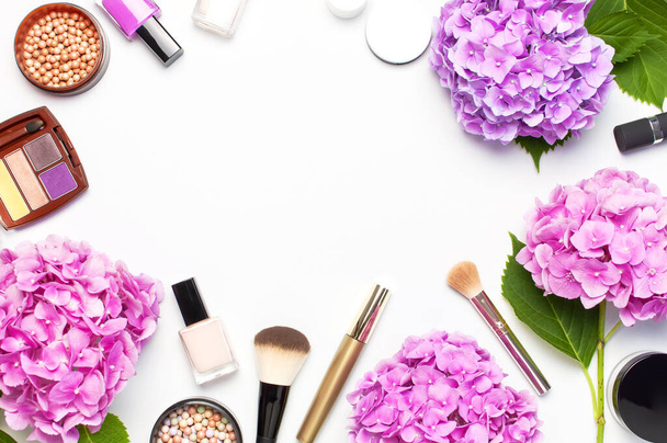 Set van decoratieve cosmetica mascara poeder Lipstick oogschaduw Blush make-up borstel Roze hortensia bloemen op lichte achtergrond bovenaanzicht platte lay-out kopiëren. Beauty blogger concept. Mode achtergrond - Foto, afbeelding