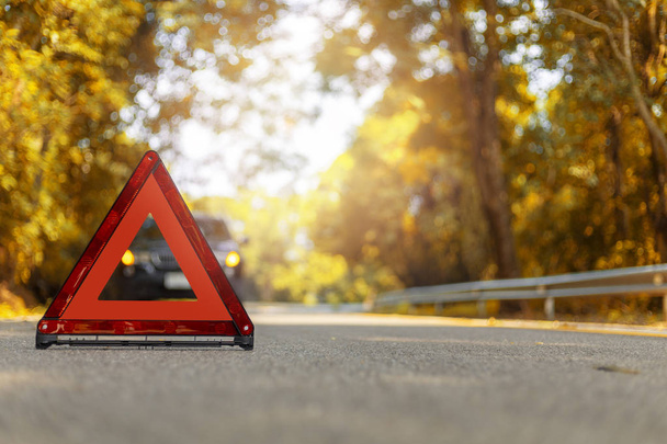 Triángulo rojo, señal roja de parada de emergencia, símbolo rojo de emergencia y parada de coche negro y aparcar en la carretera
. - Foto, Imagen