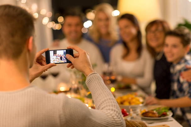 man taking picture of family at dinner party - Foto, Imagem