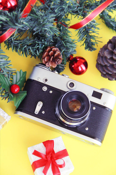 film vintage fotó kamera egy ág egy zöld fa és karácsonyi dekoráció sárga alapon - Fotó, kép