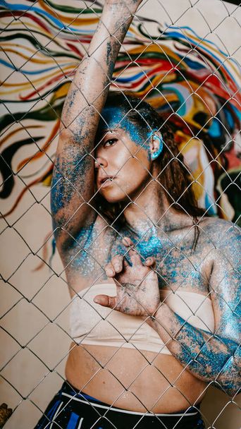 Chica morena detrás de la red. Retrato de mujer con destellos azules en la cara
 - Foto, Imagen