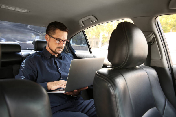 Успішний бізнесмен з ноутбуком в сучасному автомобілі
 - Фото, зображення