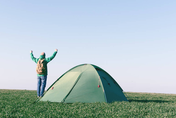 Tourist mit erhobenen Händen in der Nähe seines Zeltes - Foto, Bild