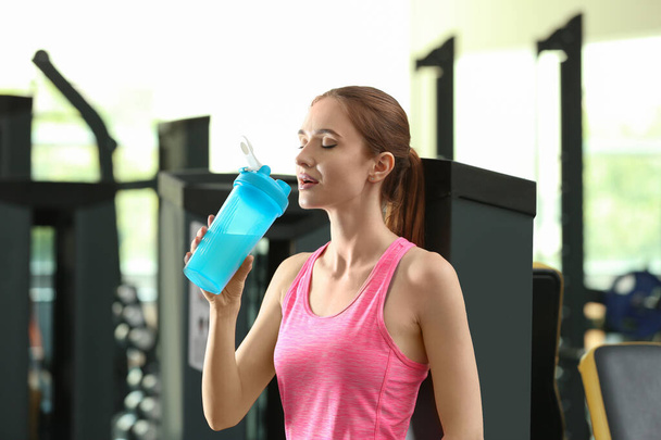 Athletic young woman drinking protein shake in gym - Fotoğraf, Görsel