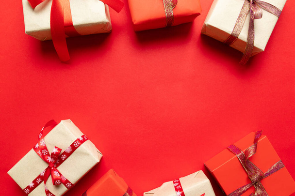 Bovenaanzicht op kerstgeschenken verpakt in cadeaupapier versierd met lint op de achtergrond. Nieuwjaar, feestdagen en viering concept - Foto, afbeelding