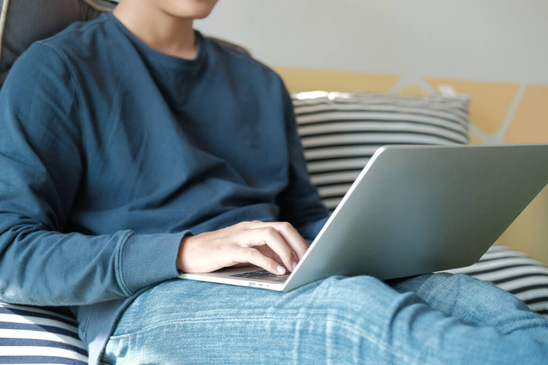 man sitting on floor using computer at home. male teenager stude - Photo, Image