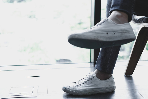 man teenager legs wearing white sneakers sitting relaxing at hom - Photo, Image