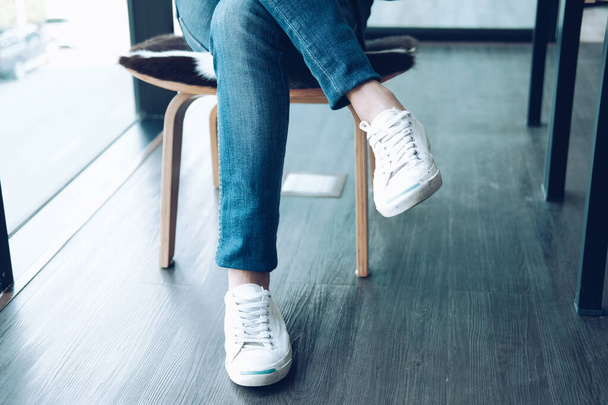 homem adolescente pernas vestindo tênis brancos sentado relaxante no hom
 - Foto, Imagem