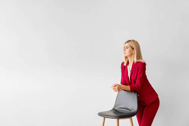 Piękna stylowa bizneswoman z krzesłem na jasnym tle - Zdjęcie, obraz