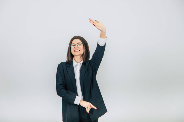 Young confident businesswoman in black suit standing, raising her hand, smiling widely. - Foto, Bild