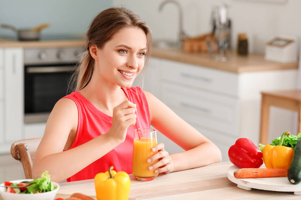 Jonge vrouw die gezond sap drinkt in de keuken. Dieetconcept - Foto, afbeelding