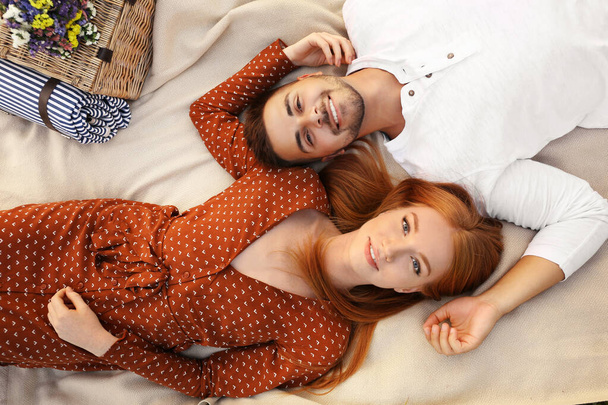 Happy young couple lying on picnic blanket, top view - Foto, Bild
