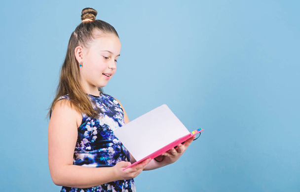 Fashion girl reading book. workbooks for writing. school diaries for making notes. small girl with pink note book. school child with exercise book. looking inside. schoolgirl holding lesson books - Foto, Bild