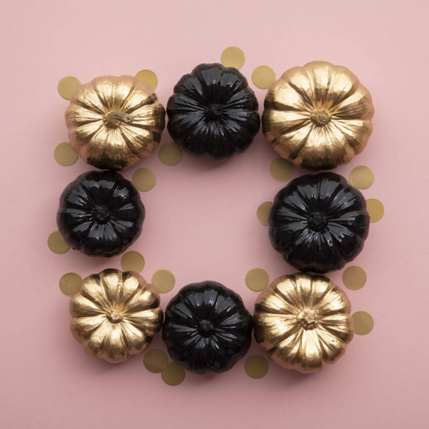 Gold and black pumpkins on pastel pink. Flat lay thanksgiving composition - Photo, image