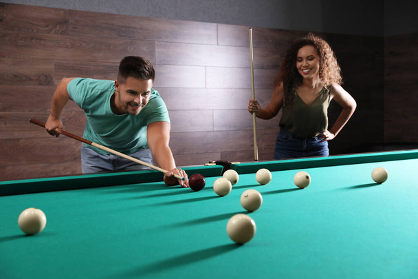 Young man and woman playing billiard indoors - Foto, Imagem