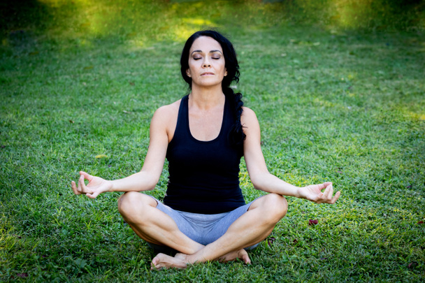 Brunette woman doing yoga in a park - 写真・画像
