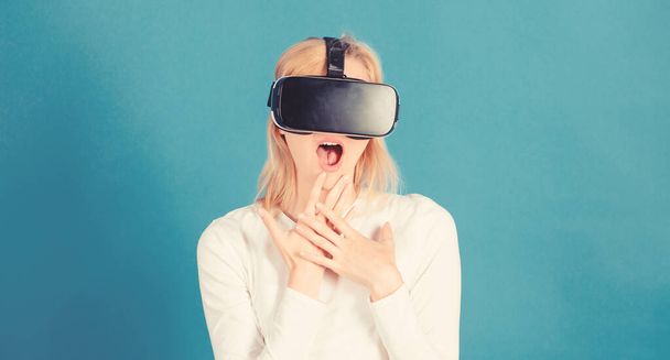 Woman watching virtual reality vision. Woman using VR device. Woman wearing virtual reality goggles in blue background. Futuristic 3d. - Foto, afbeelding