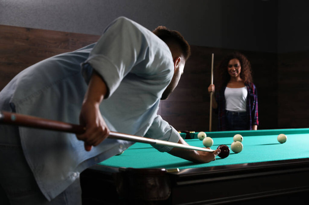 Young man and woman playing billiard indoors - Zdjęcie, obraz