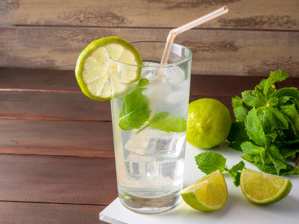 One glass of mojito cocktail with fresh lime and mint on a wooden background - 写真・画像