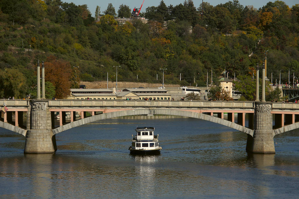 tramwaj rzeczny pływający pod kamiennym mostem wzdłuż rzeki - Zdjęcie, obraz