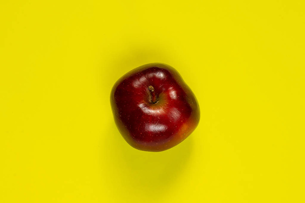 one red apple on an isolated yellow background - Fotoğraf, Görsel