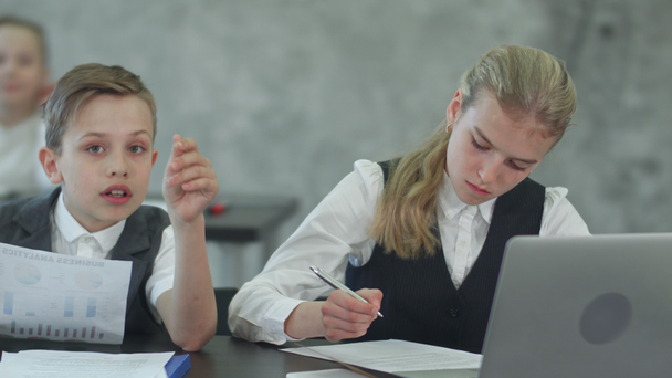 Niños de negocios que trabajan con documentos y con laptop
 - Metraje, vídeo