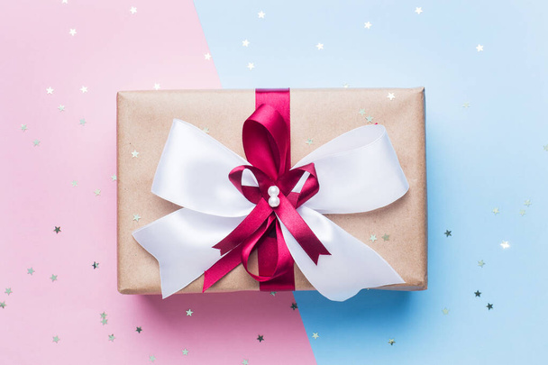 Gift or present box with a big bow on a pink blue table top view. Flatlay composition for Christmas birthday, mother day or wedding. - Fotografie, Obrázek