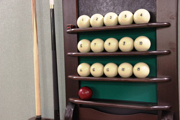 Dos taco, muchas bolas blancas y una bola marrón en el estante de la bola para jugar billar ruso
 - Foto, Imagen
