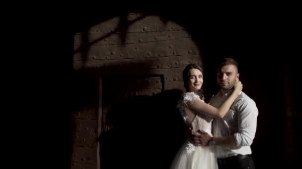 Казкова весільна пара стоїть біля чорної стіни з тіні від металевих воріт. Дія. Портрет молодої нареченої і нареченої перед темною стіною
. - Кадри, відео