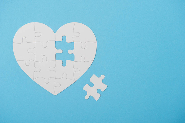 Forme de coeur de puzzle blanc avec pièce manquante, sur bleu
 - Photo, image