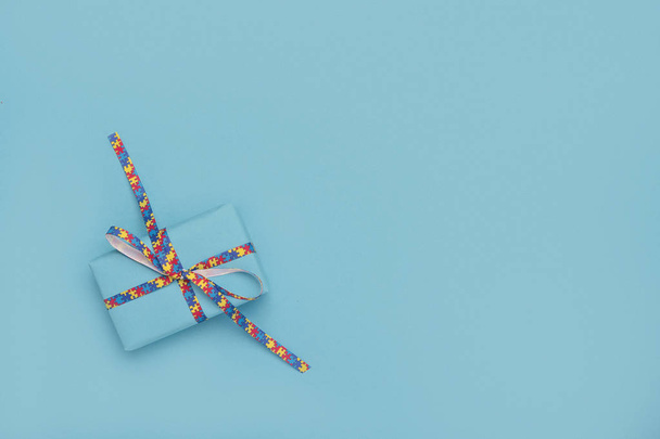 世界の自閉症は、贈り物と青の背景にパズルパターンリボンを認識 - 写真・画像