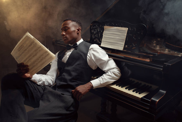 afrikanischer Pianist mit Notenheft, Jazzmusiker.  - Foto, Bild