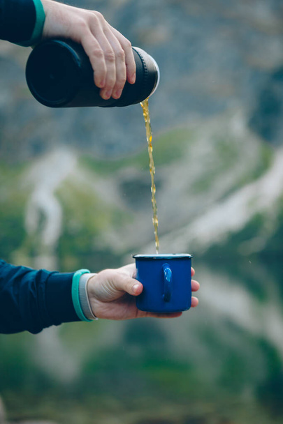 nalewanie herbaty z termosu do filiżanki wędrówki koncepcja jezioro z górami na tle - Zdjęcie, obraz