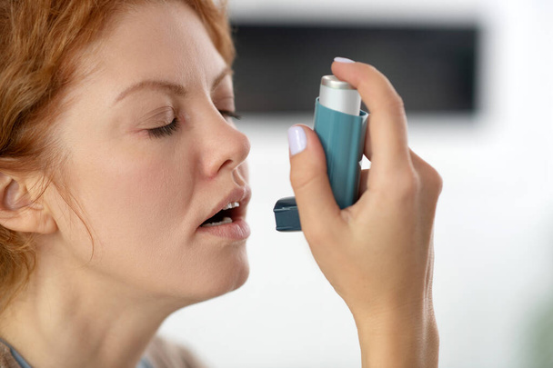 Young woman closing her eyes while applying inhalator - Zdjęcie, obraz