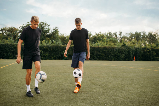 Футболисты-мужчины тренируются с мячами на поле. Футболисты на открытом стадионе, командная тренировка перед игрой
 - Фото, изображение