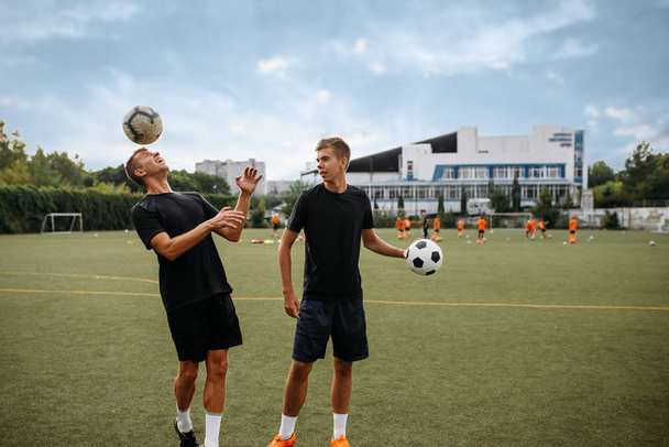 Férfi focisták edzenek golyókkal a pályán. Focisták a szabadtéri stadionban, csapatedzés játék előtt  - Fotó, kép