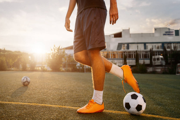 Piłkarz z piłką na boisku o wschodzie słońca. Piłkarz na stadionie, trening przed meczem, trening piłki nożnej - Zdjęcie, obraz