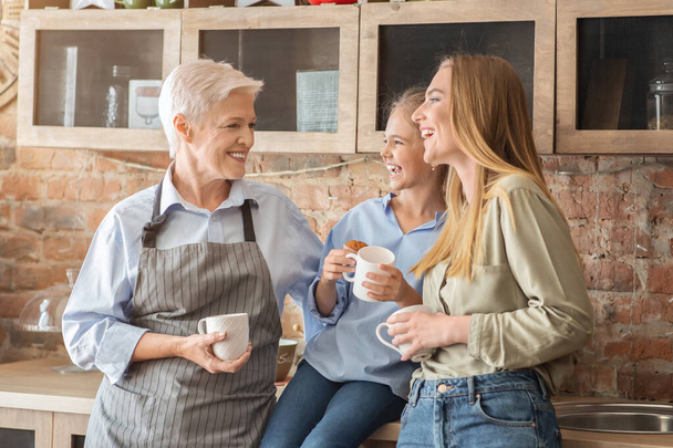 Female family drinking tea and talking at kitchen - Photo, Image