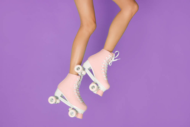 Long legs in a vintage pink roller skate isolated on violet background. - Photo, Image