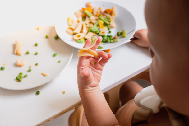 One-year-old baby eats the food from his plate directly with his - 写真・画像