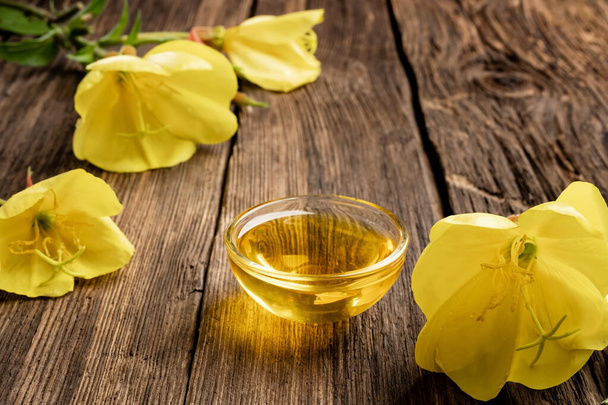 Evening primrose oil and fresh blooming plant  - Photo, Image