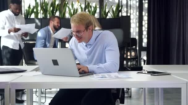 Slow motion of likable high-skilled smiling businessman which working at his computer in the modern office room - Кадри, відео