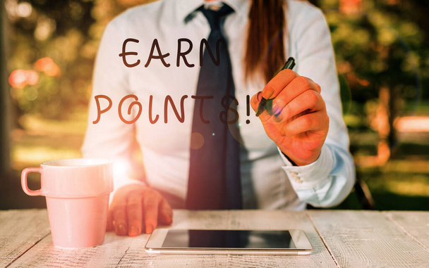 Writing note showing Earn Points. Business photo showcasing collecting scores in order qualify to win big prize Female business person sitting by table and holding mobile phone. - Photo, Image