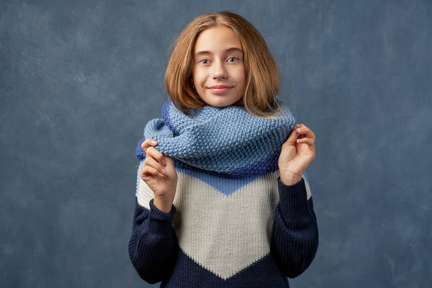 Teenage girl blonde in warm sweater isolated wall - Photo, image
