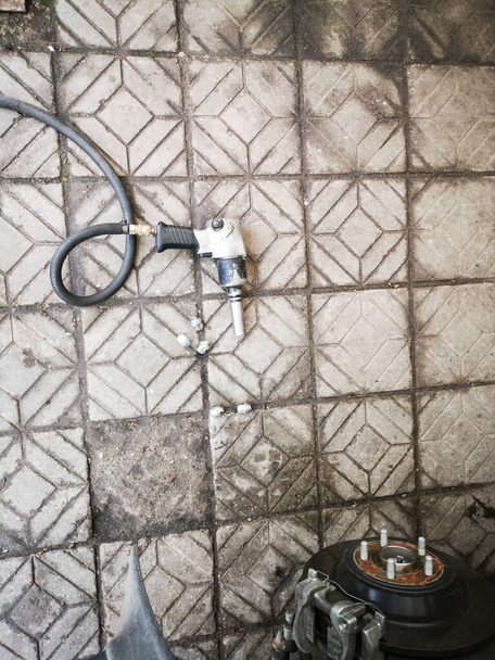 Chave pneumática com uma mangueira longa deitada no chão de telhas de pedra, vista superior
 - Foto, Imagem