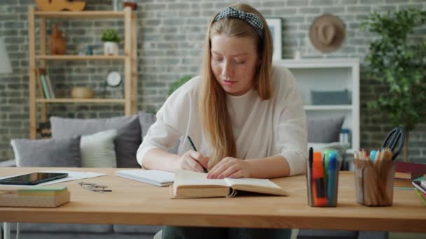 Smart young lady working at project at home writing reading book at desk - Imágenes, Vídeo
