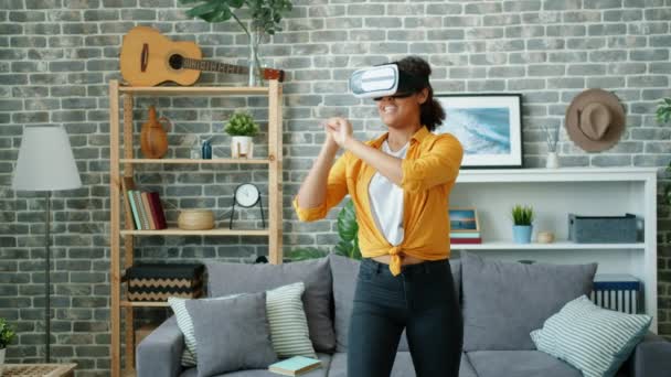 Movimento lento da jovem mulher feliz jogando jogo usando óculos de realidade virtual
 - Filmagem, Vídeo