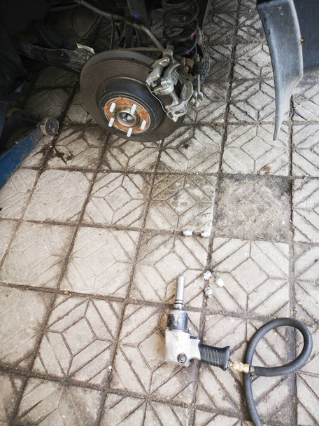 pneumatikus csavarkulcs a betonon félre car jack lift és egy darab autó gumiabroncs kijavításához rozsdás fém autó gumiabroncs dióval. - Fotó, kép