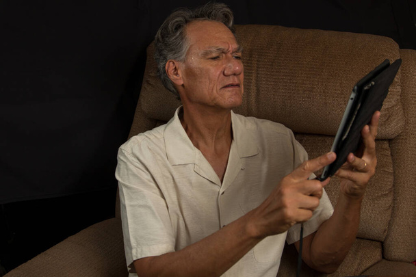Mature Gentleman Siting in an Easy Chair Looking at his Smart Tablet - Photo, Image